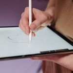 Hand using stylus pen on a tablet for sketching, showcasing modern digital design tools.